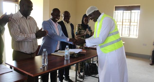 The Contractor for Kinumi Seed Sec. School, handing over School Keys to MP for Buruli County, Hon. Aled Ronald Akugizibwe during the Technical Handover of the Infrastructures